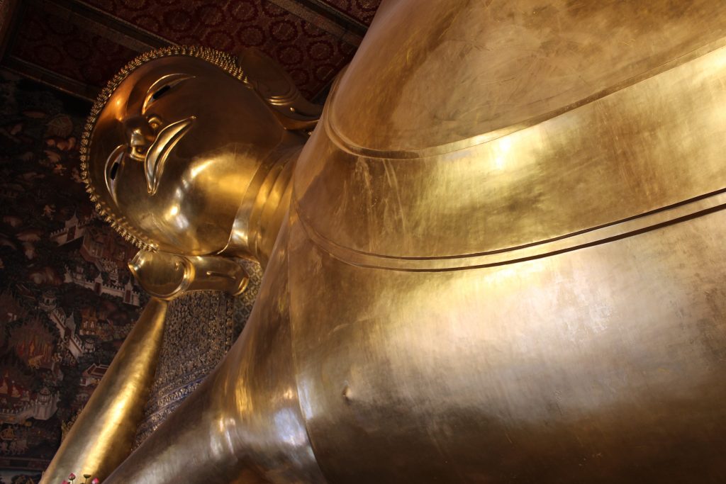 The Grand Palace The Reclining Buddha is really really big guys. Its beautiful and just hanging out with his eyes open wondering what the big deal is. The sound of clinking coins and chanting surround you