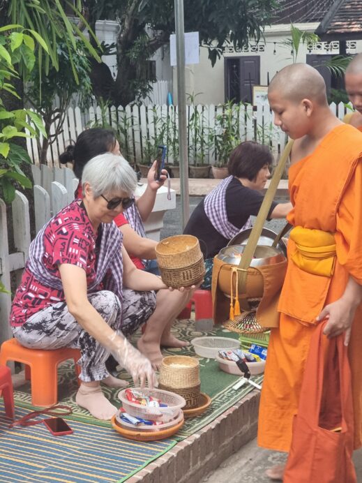 monk in orange robes getting alms