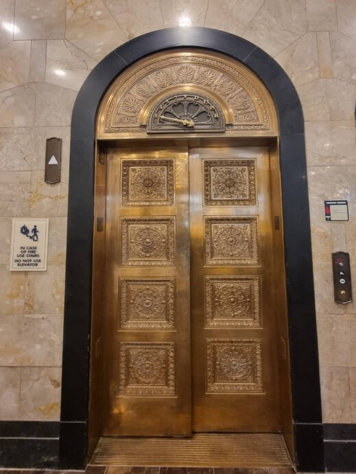 bronze elevator art floor detail over door Hotel Saint Louis