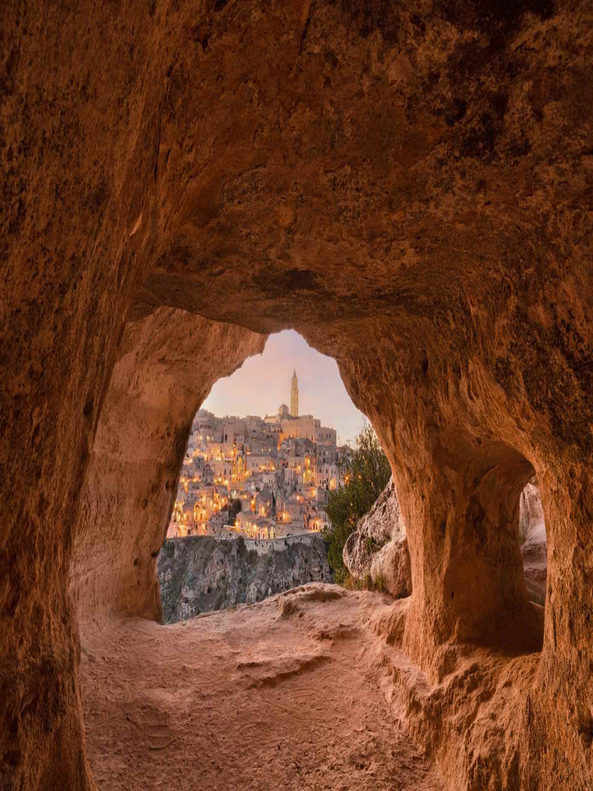 Matera, Italy as seen from within an ancient cave at dusk featured image